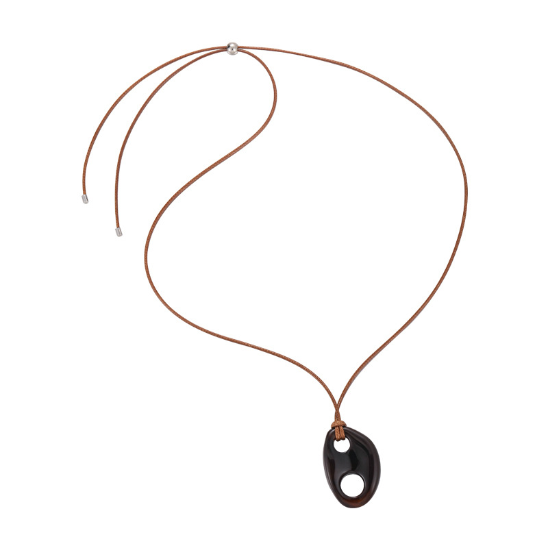 Långt svart snörhalsband med trynformad hartsdetalj